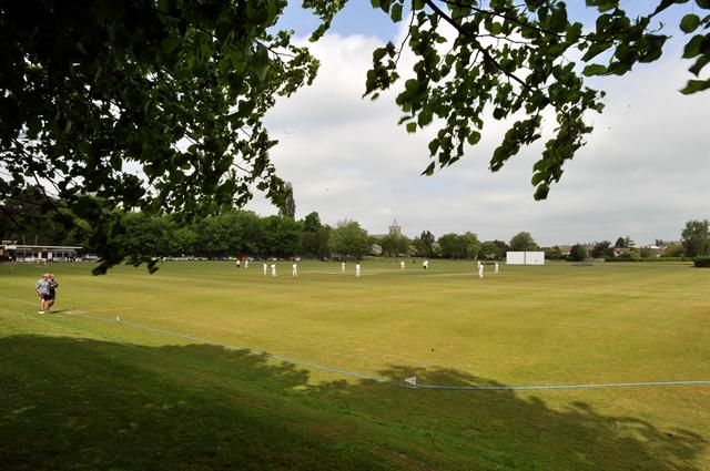 A group of people are playing cricket on a field.