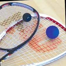 Two squash rackets and a ball are sitting on a wooden table.