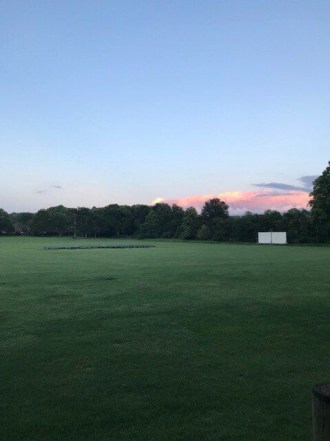 A large grassy field with a sunset in the background