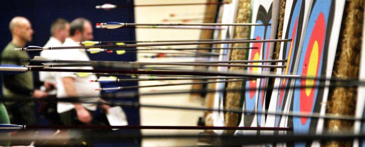 A group of people are standing in front of a archery target.