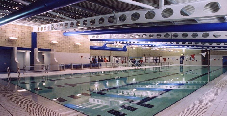 A large indoor swimming pool with people swimming in it