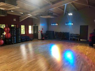 A large gym with a wooden floor and a lot of exercise equipment.