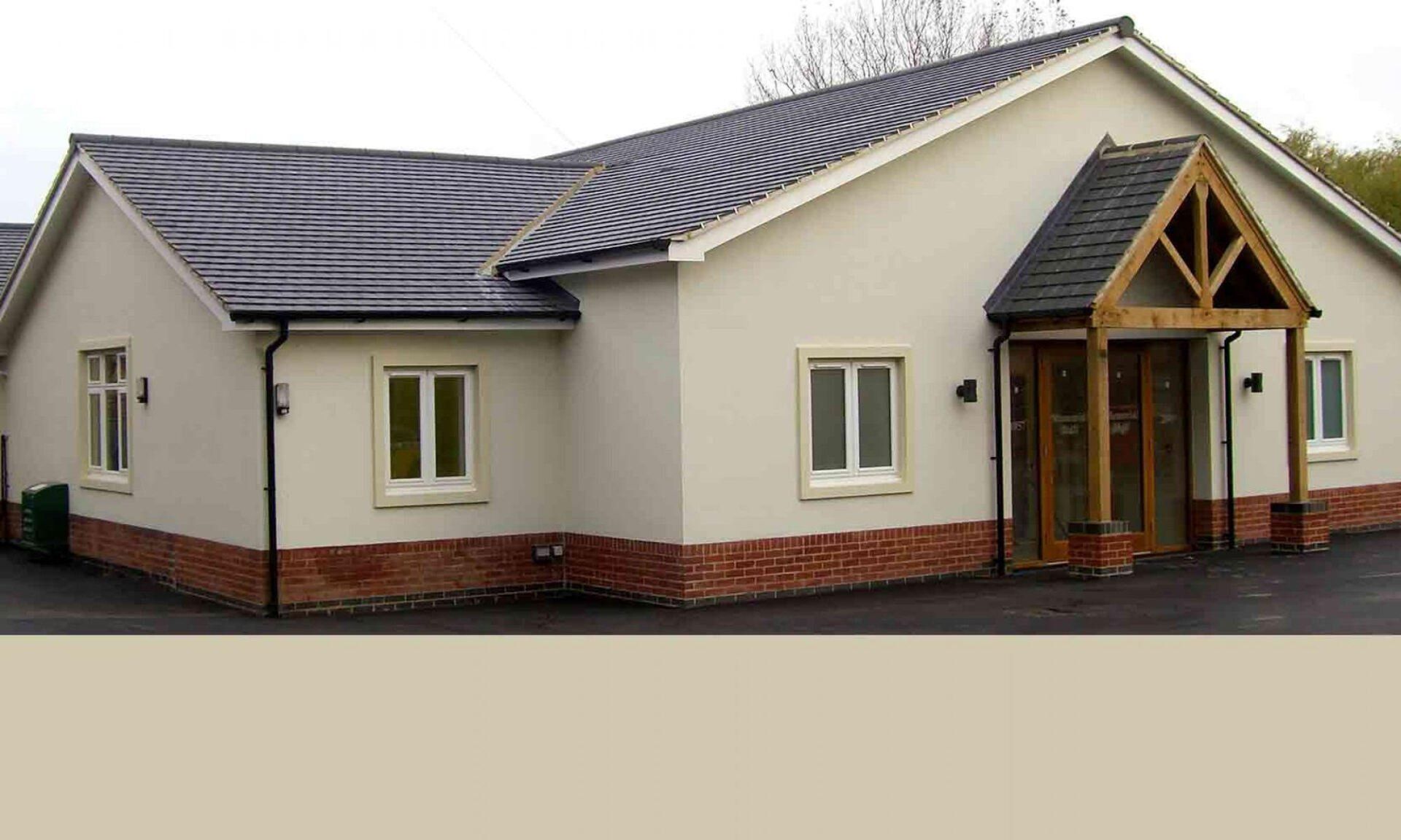 A white house with a black roof and a wooden porch