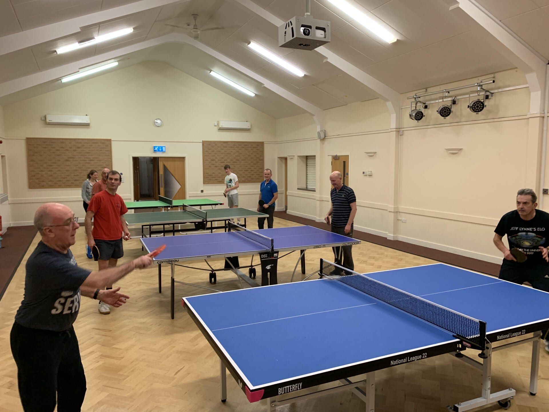 A group of people are playing ping pong in a large room.