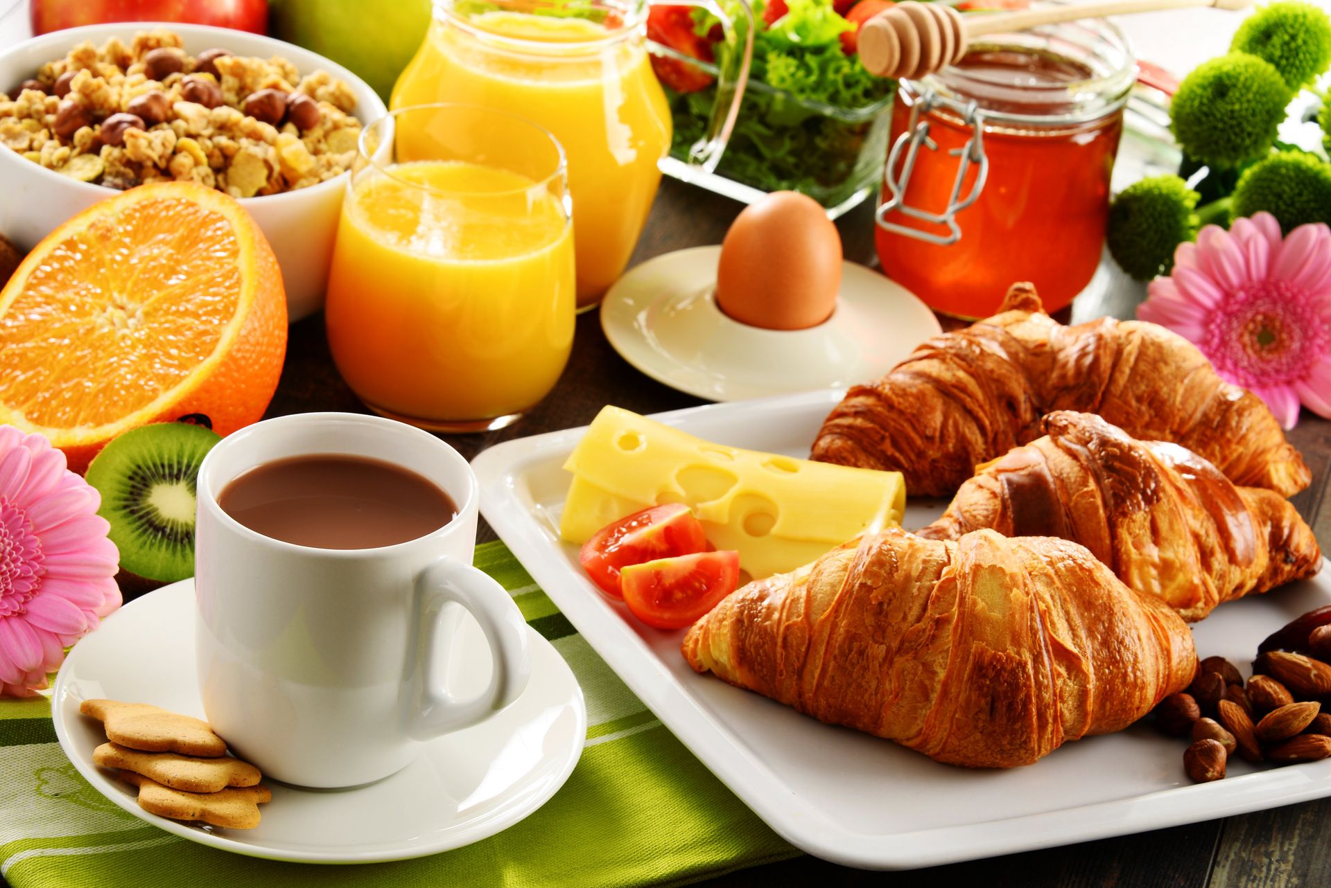Frühstücksangebot: Kaffee, Saft, Croissants, Obst, Müsli, Ei, Käse, Honig.
