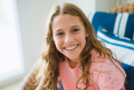 girl smiling on chair with blue pillows