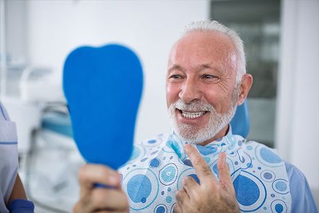elder with mirror looking at his teeth