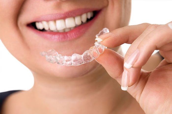 woman smiling with invisalign in hand