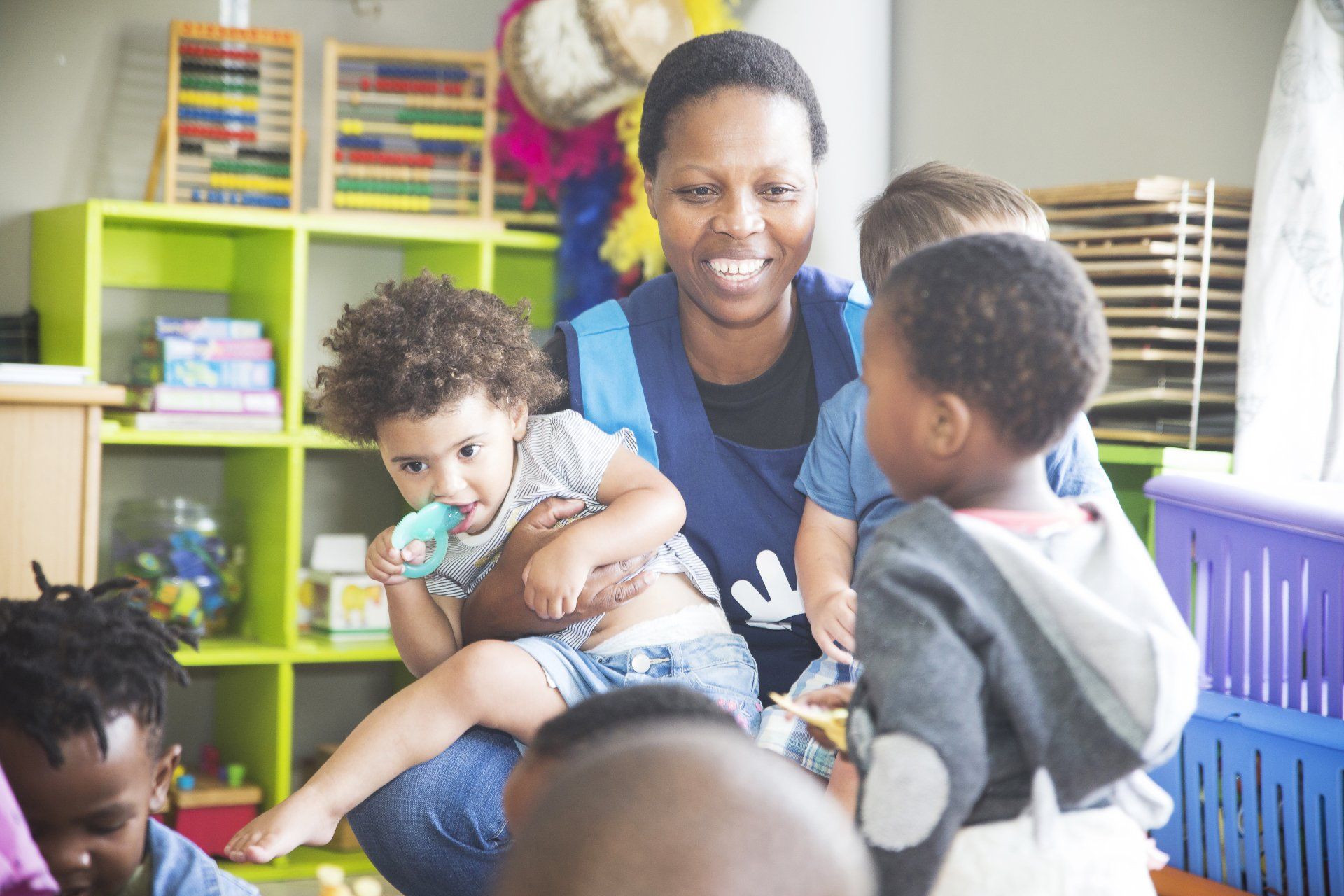 A woman is holding a baby in her arms in a classroom.