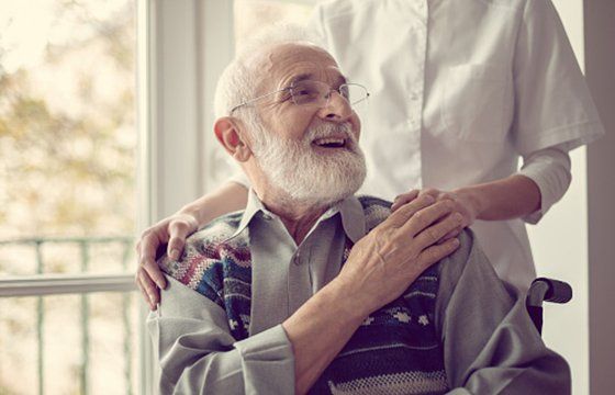 Senior Man Sitting Holding His Nurse's Hand — Kenosha, WI — Home Care Services