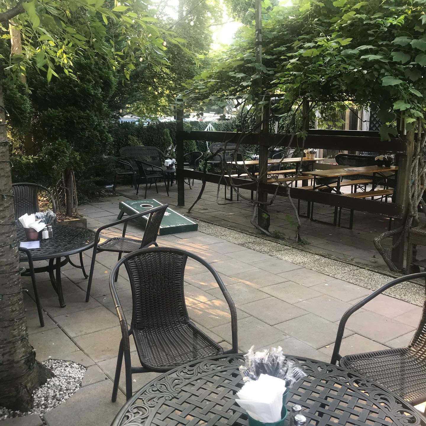 outdoor beer garden with tables and cornhole game