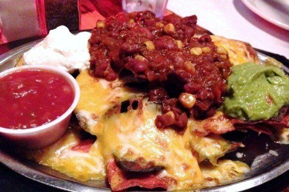 nachos loaded with cheese and chili served with salsa, sour cream and guacamole