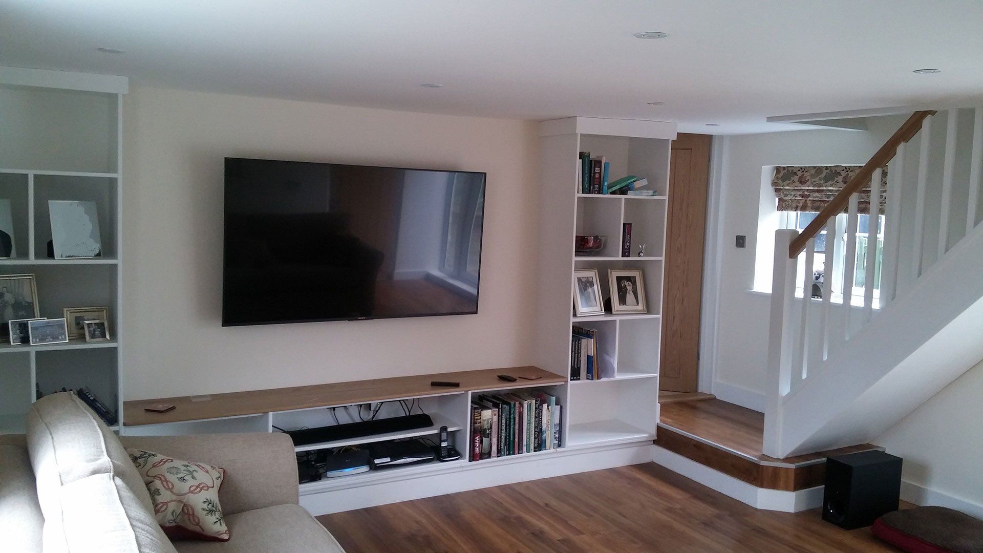 A living room with a couch and a flat screen tv on the wall.