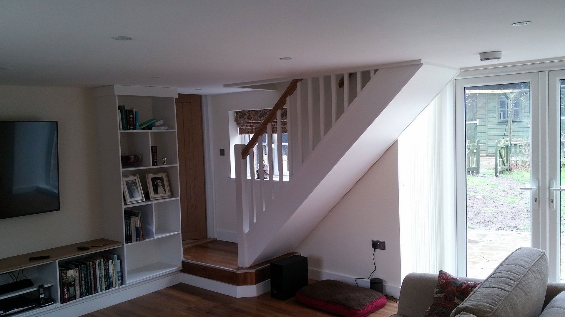 A living room with a staircase and a flat screen tv.