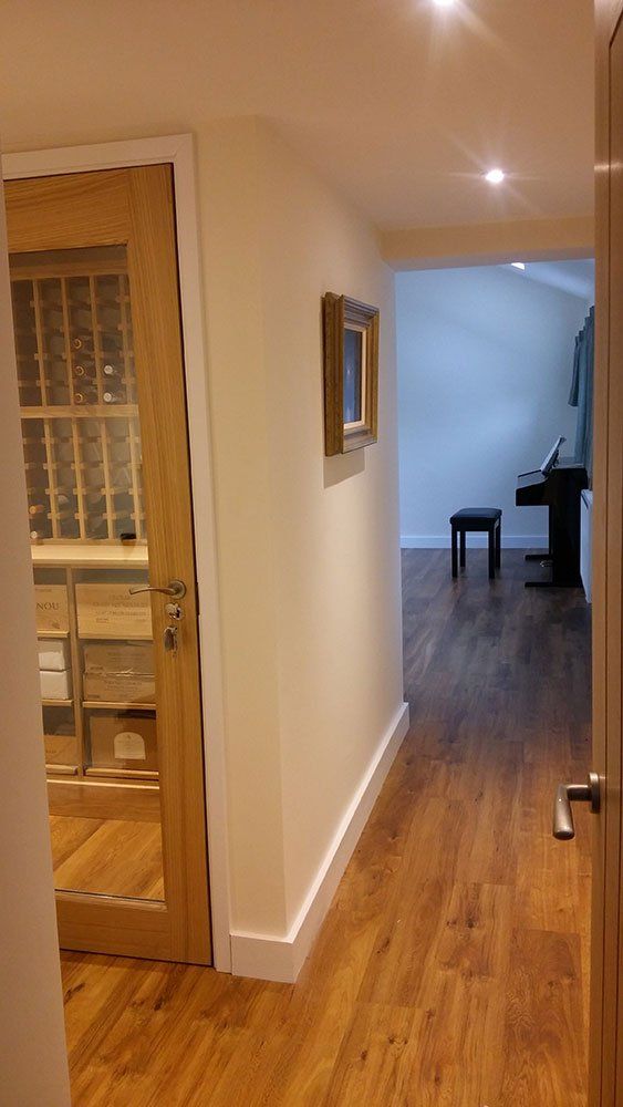 A hallway with hardwood floors and a glass door leading to a living room.