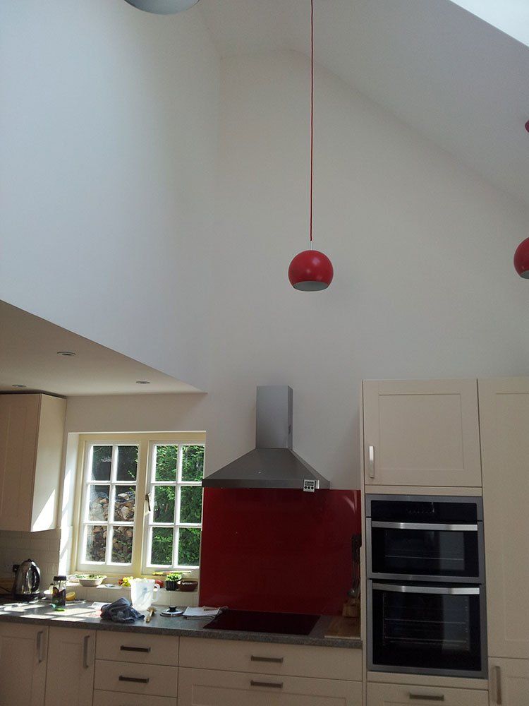 A kitchen with white cabinets and a red stove top oven