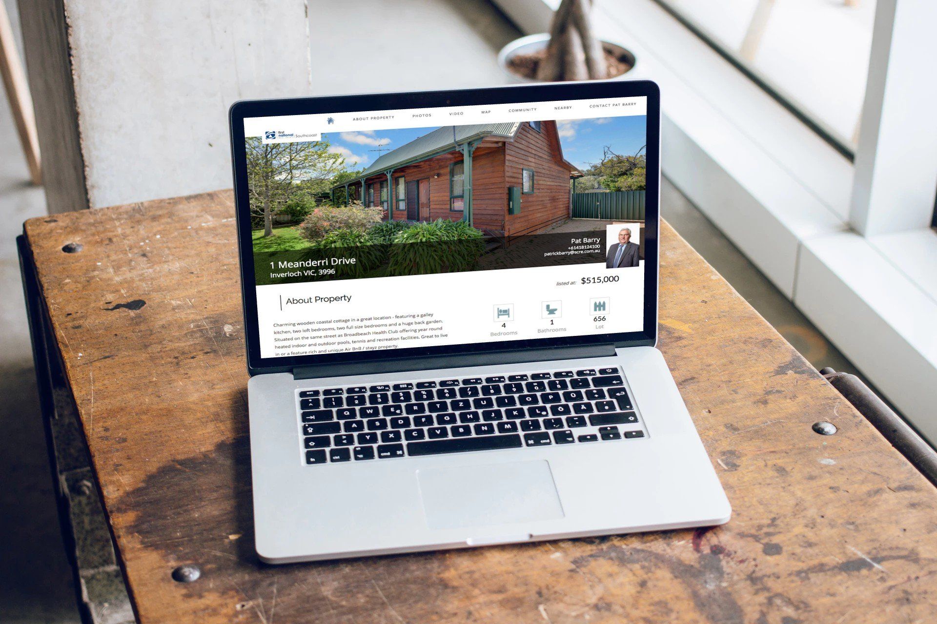 Laptop on a wooden table displaying a house listing website