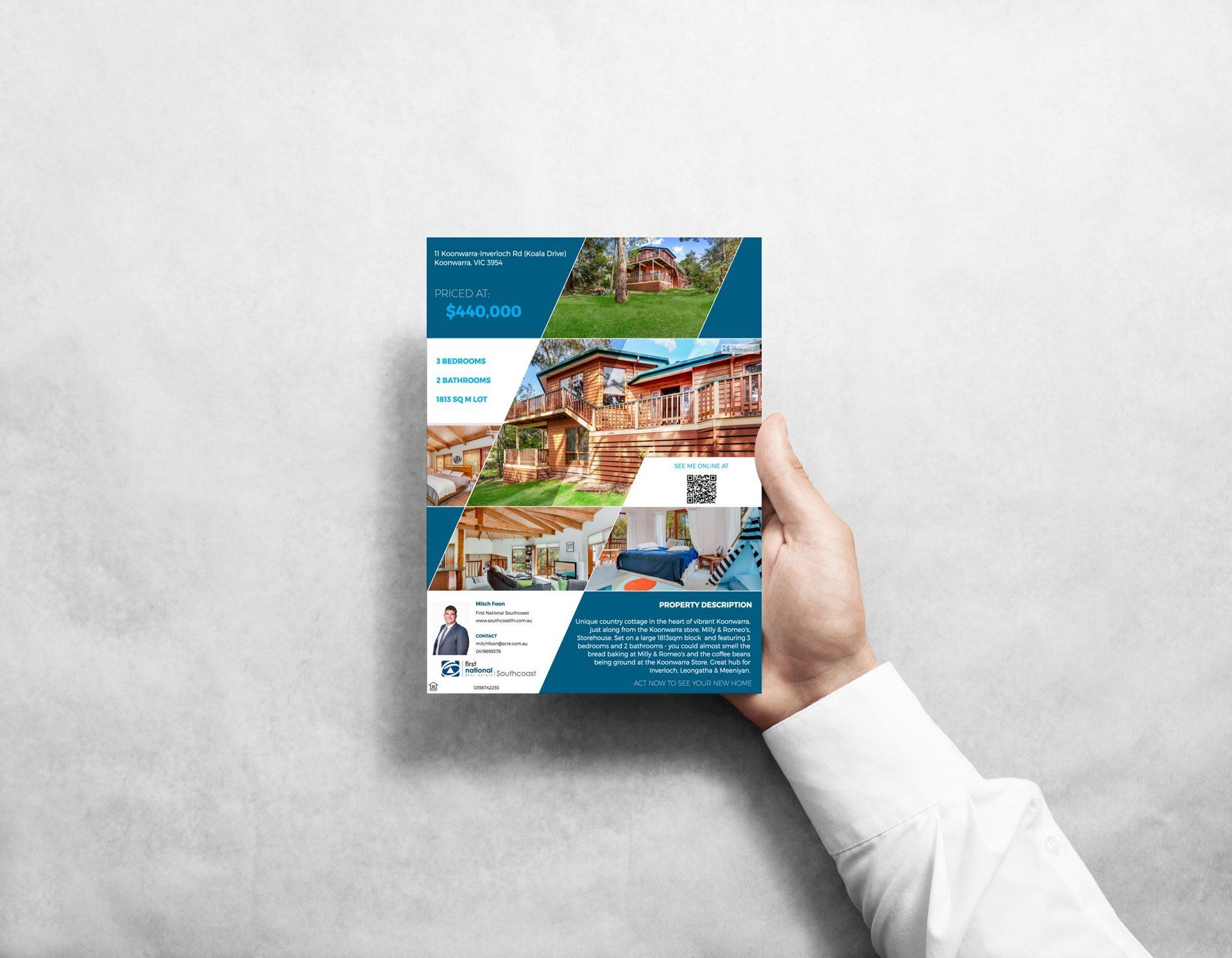 Hand holding a blue brochure with photos and text against a gray background