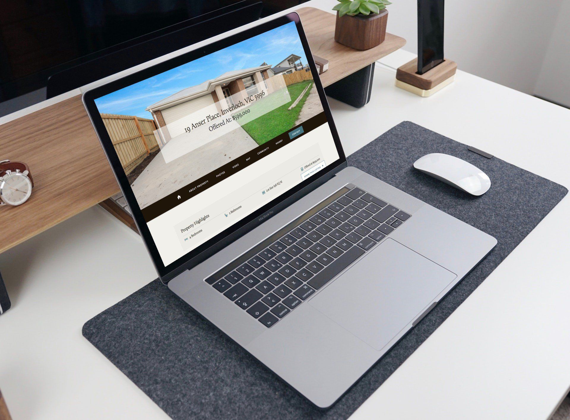 Laptop on a desk with a webpage open, beside a mouse and gray desk mat