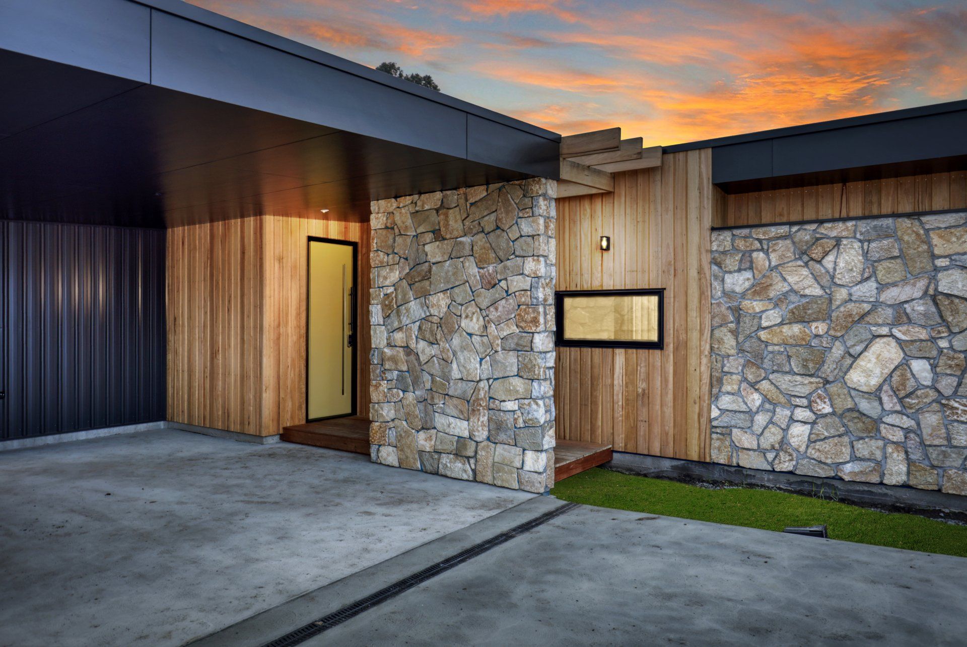 Modern house exterior with stone and wood facade at sunset