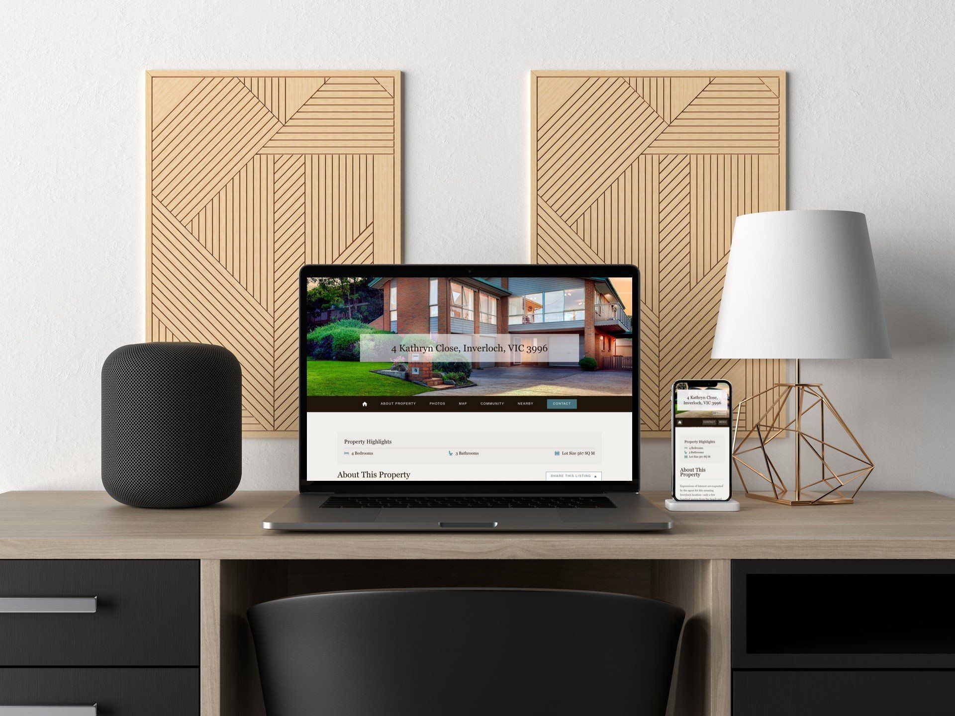 Modern desk setup with laptop, black speaker, lamp, and framed wall art in a minimalist room