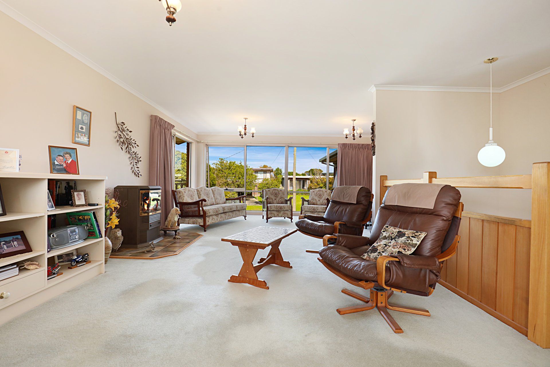 Bright living room with brown recliners, a white rug, and a large window overlooking the water