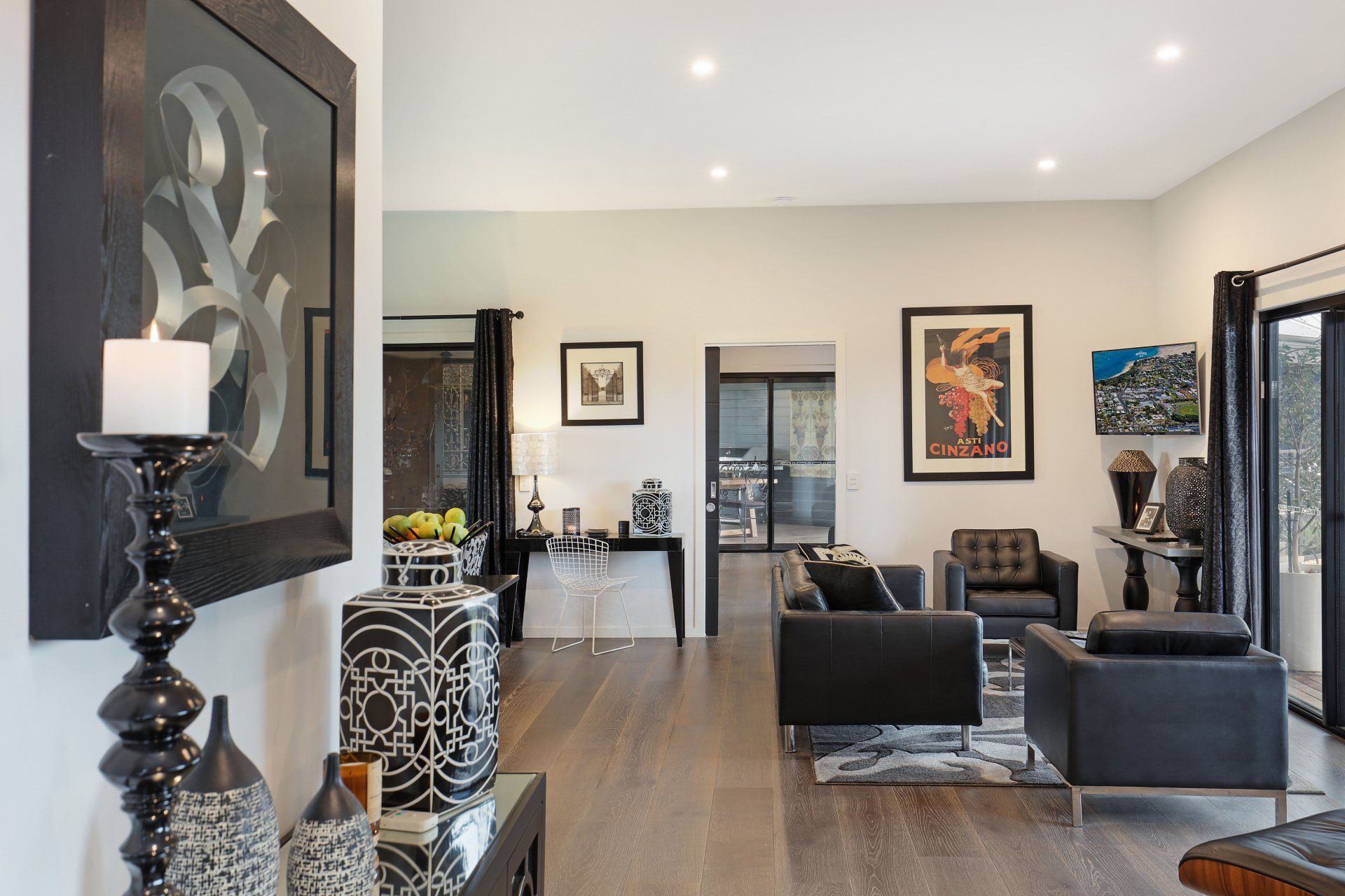 Modern living room with dark furniture, wall art, and a large mirror, viewed from the entryway