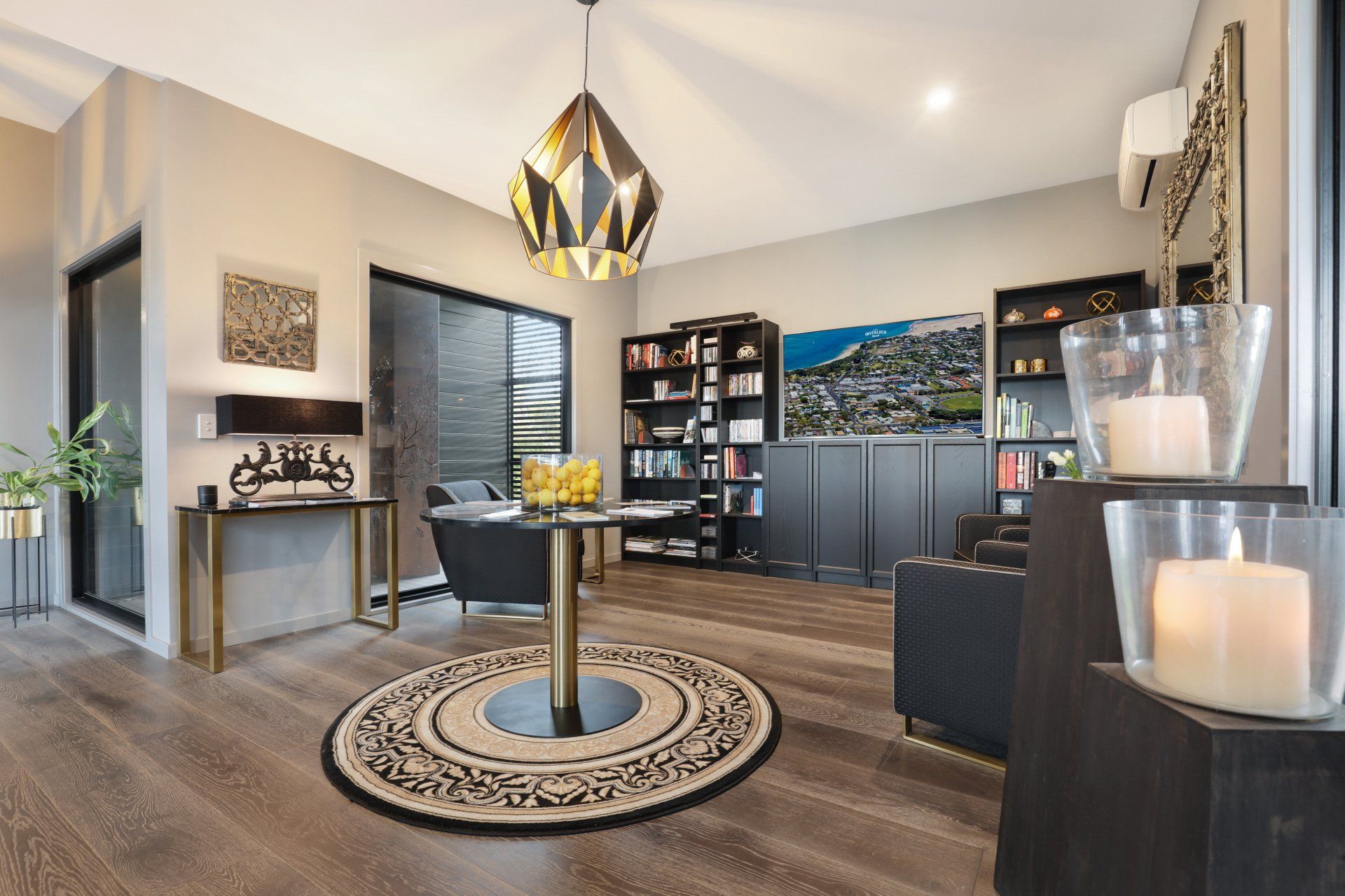 Modern living room with round rug, dark furniture, fireplace, wall art, and large windows