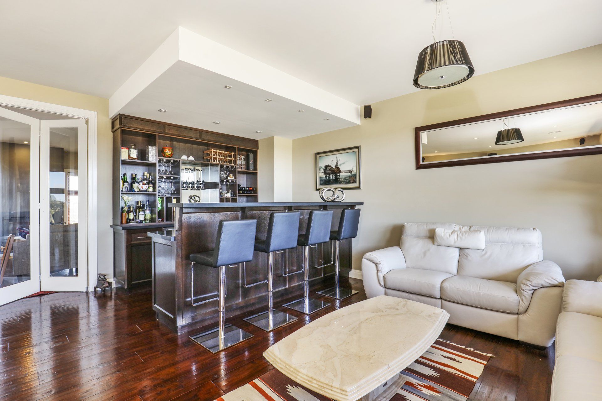Modern living room with bar seating, sofa, coffee table, and hardwood floors