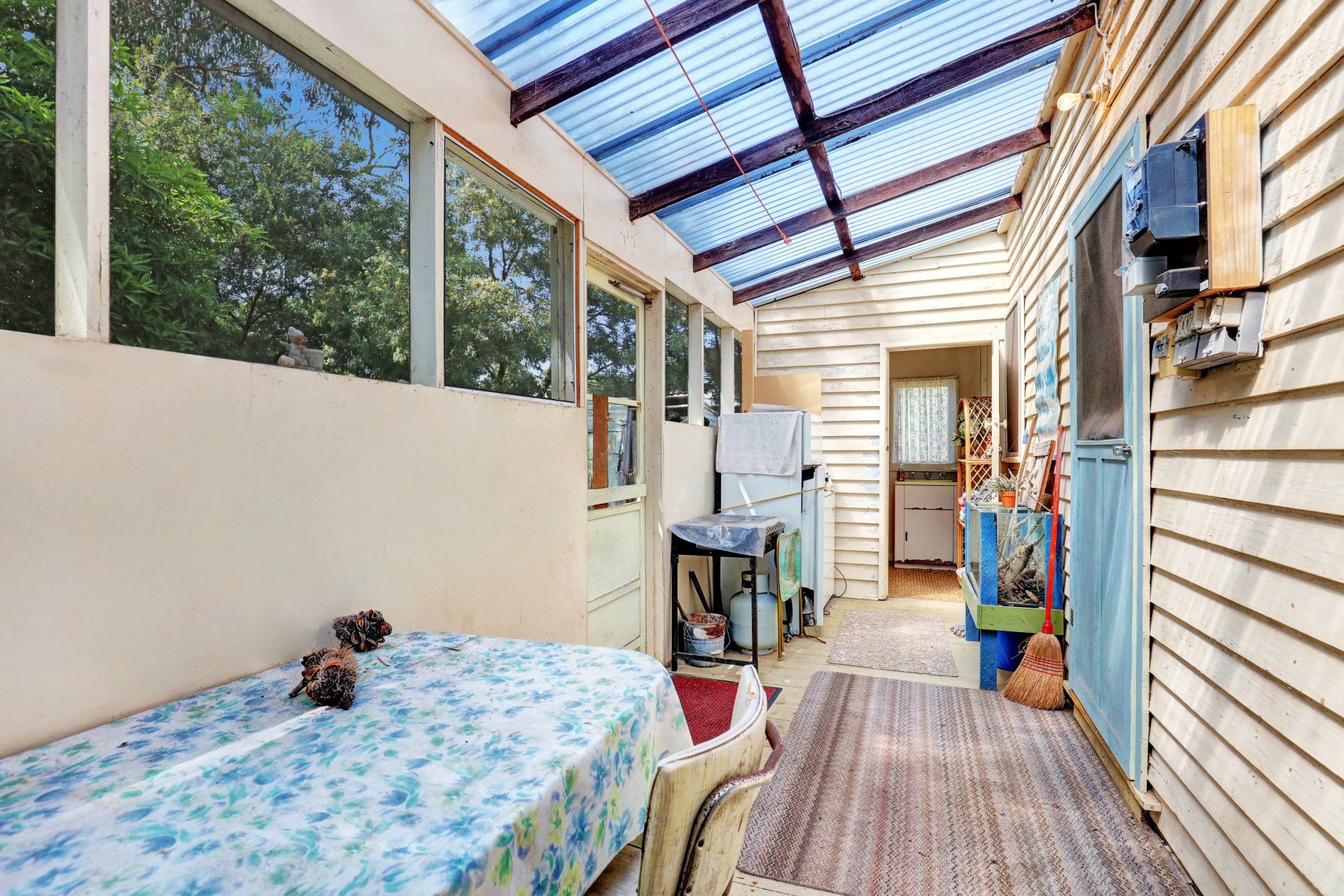 Covered outdoor corridor with a bed, rug, laundry area, and blue translucent roof panels