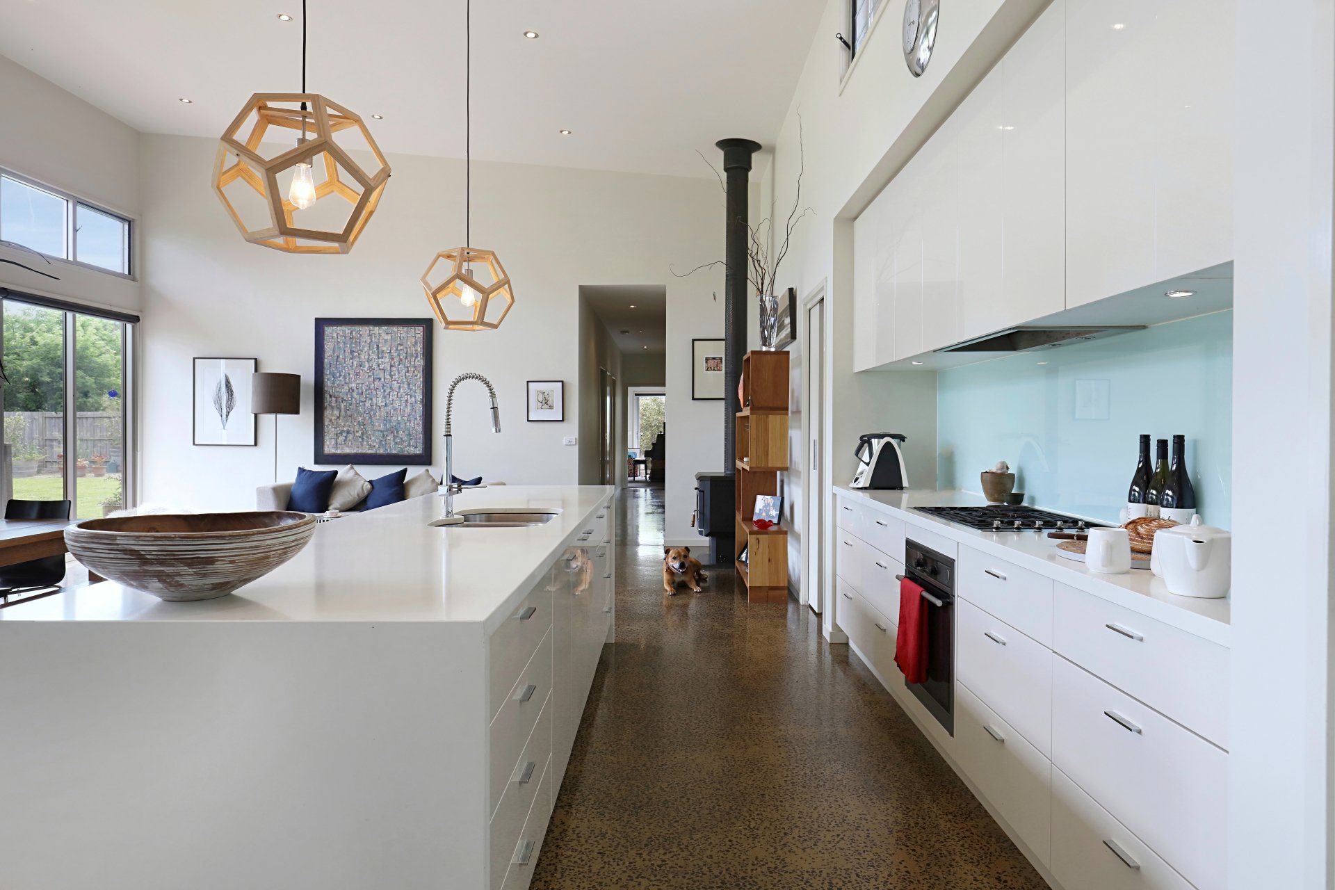 Modern kitchen with white island, wood floor, pendant lights, and stainless steel appliances