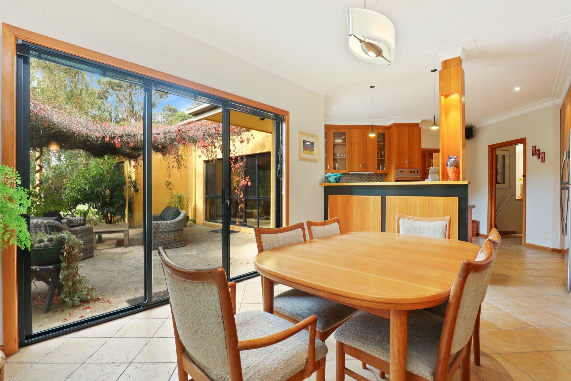 Bright dining area with wooden table, sliding glass doors, and a view of a patio garden
