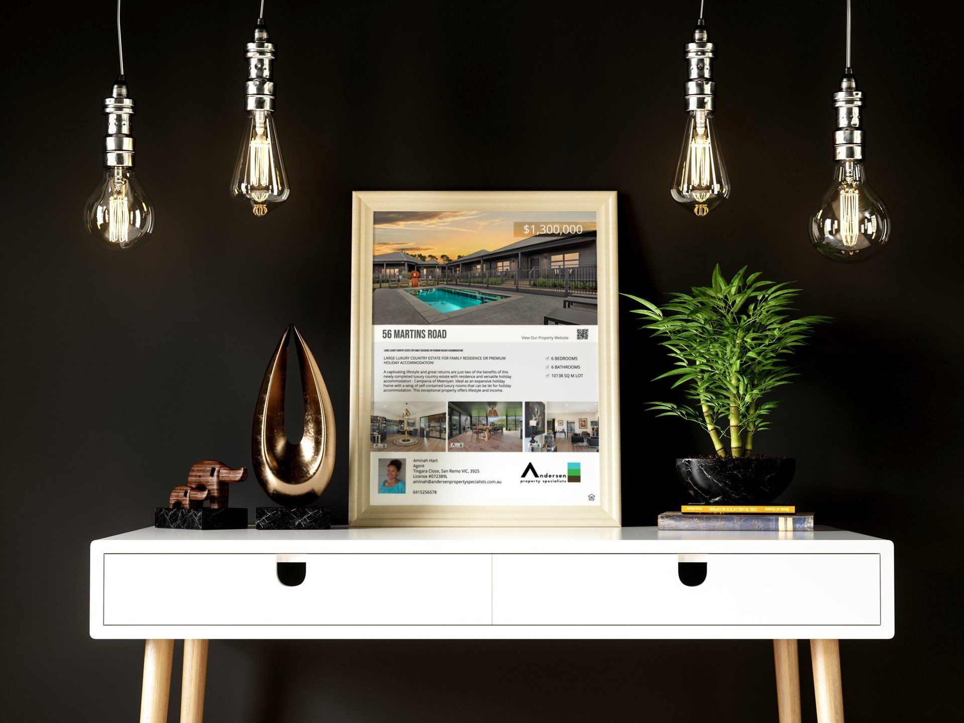 Minimalist white console table with framed art, decor, and hanging pendant lights on a dark wall