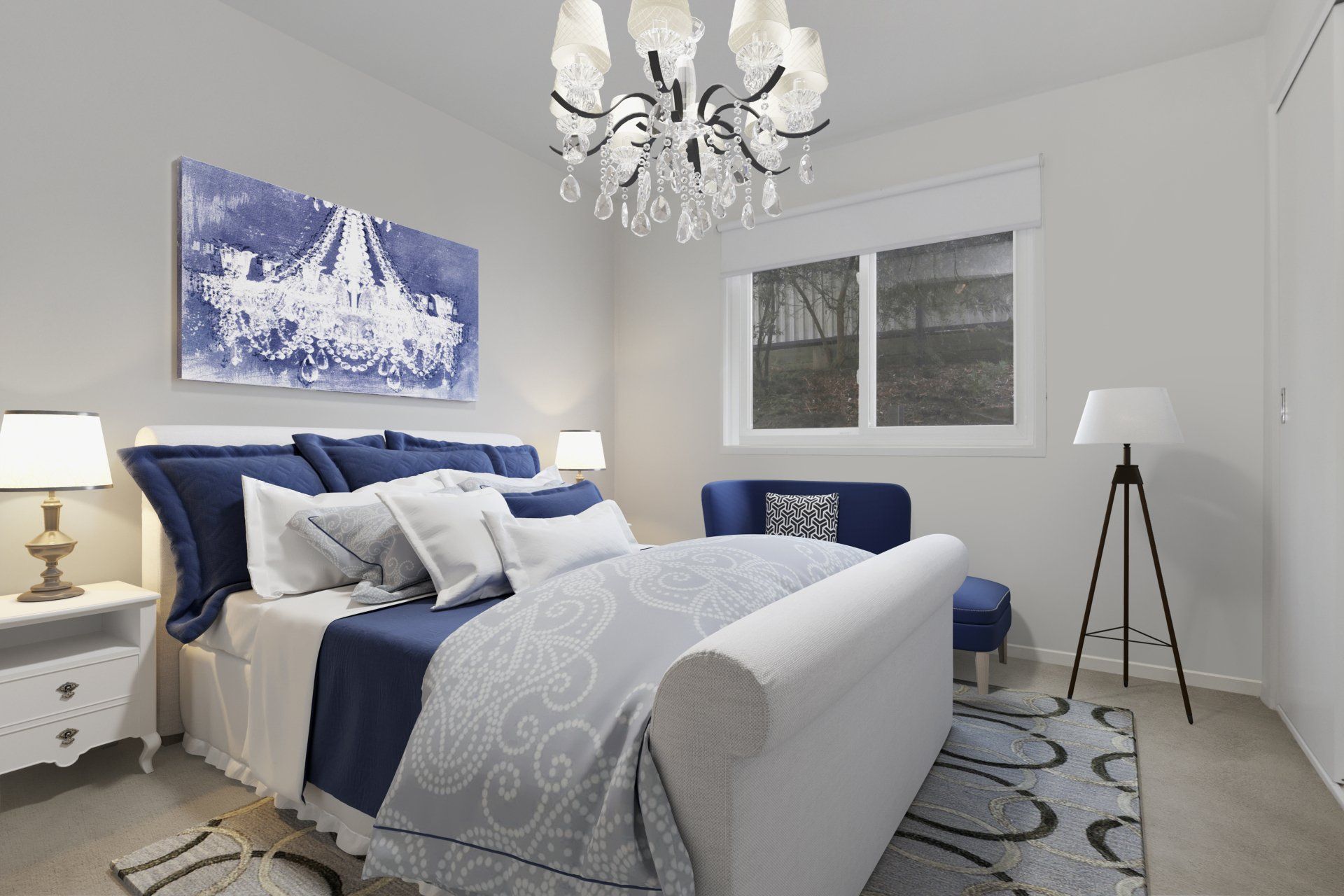Bright bedroom with navy bedding, white walls, chandelier, and a window beside a tripod lamp.