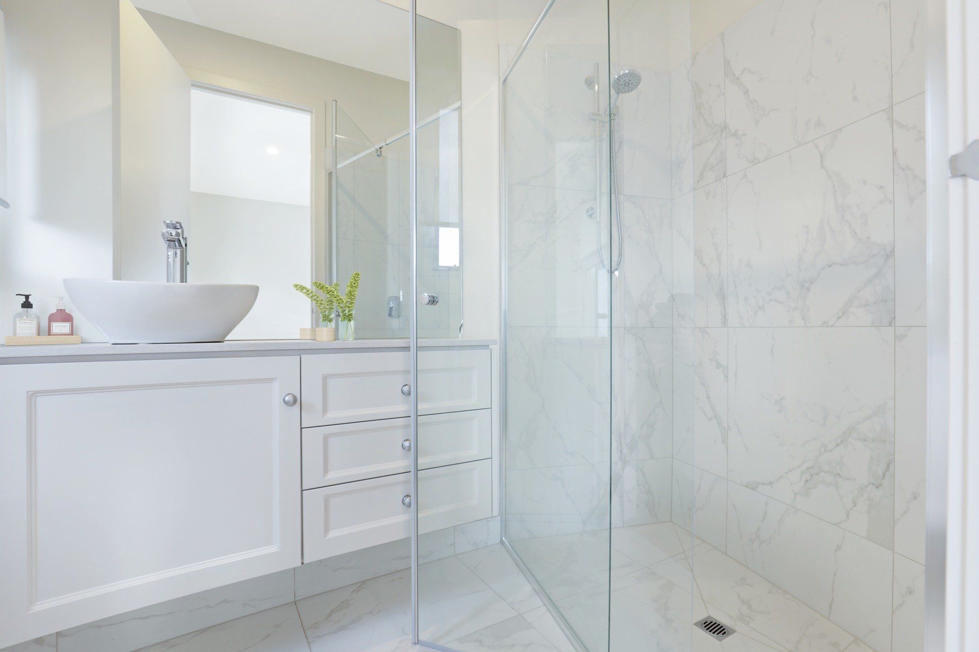 Bright modern bathroom with glass shower, white vanity, and vessel sink