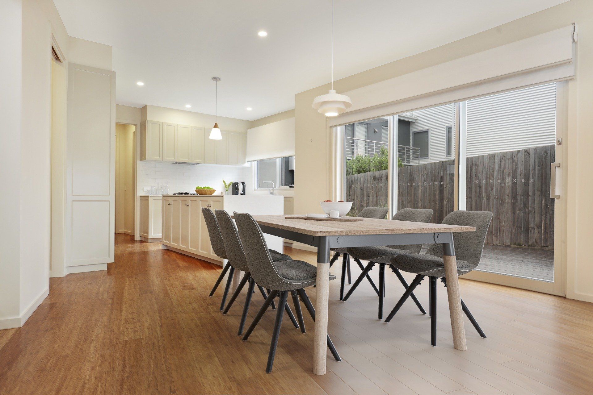 Bright dining room with a table and chairs, open kitchen, and sliding glass doors to a patio.