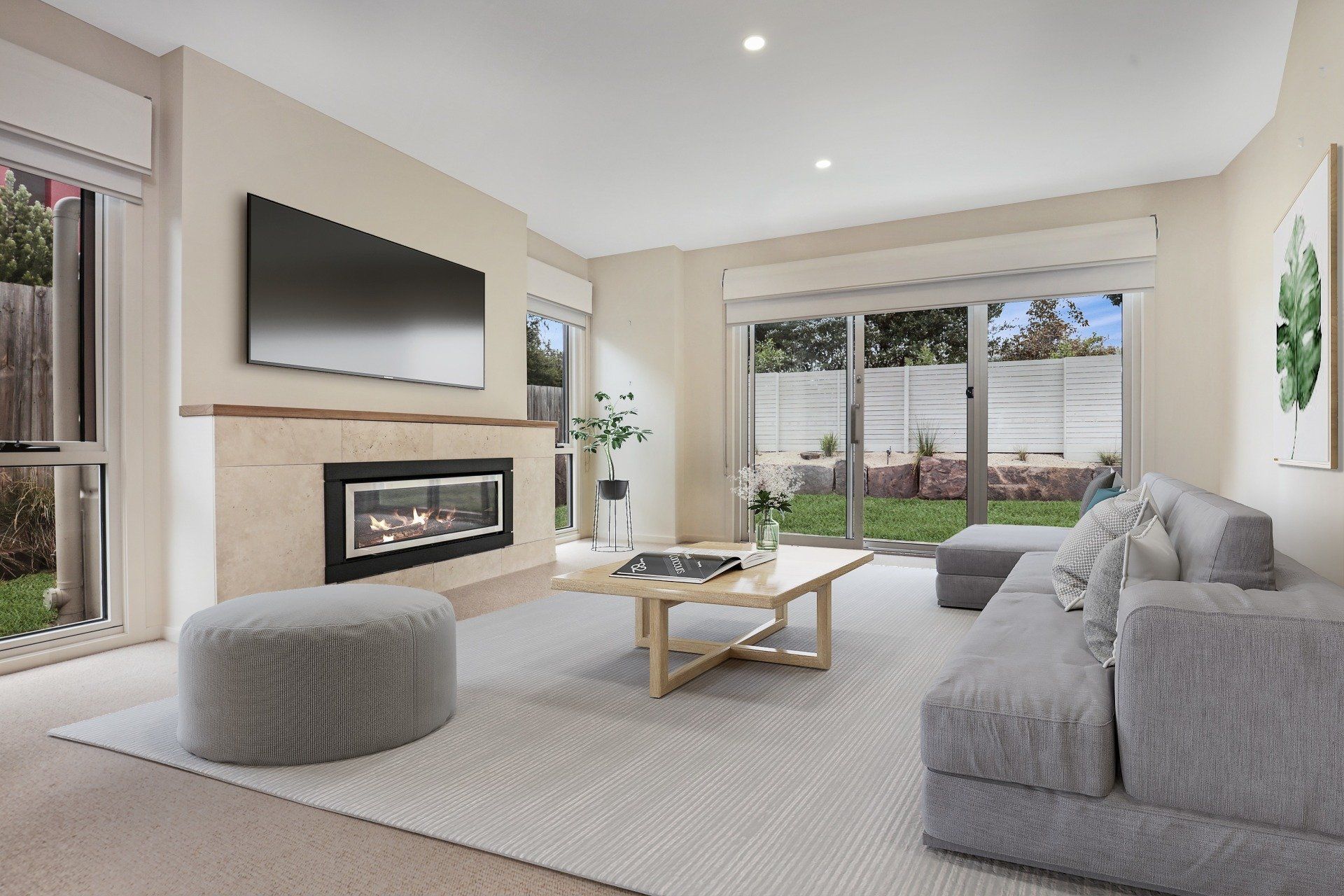 Modern living room with gray sectional, wall-mounted TV, fireplace, and sliding glass doors to a patio.
