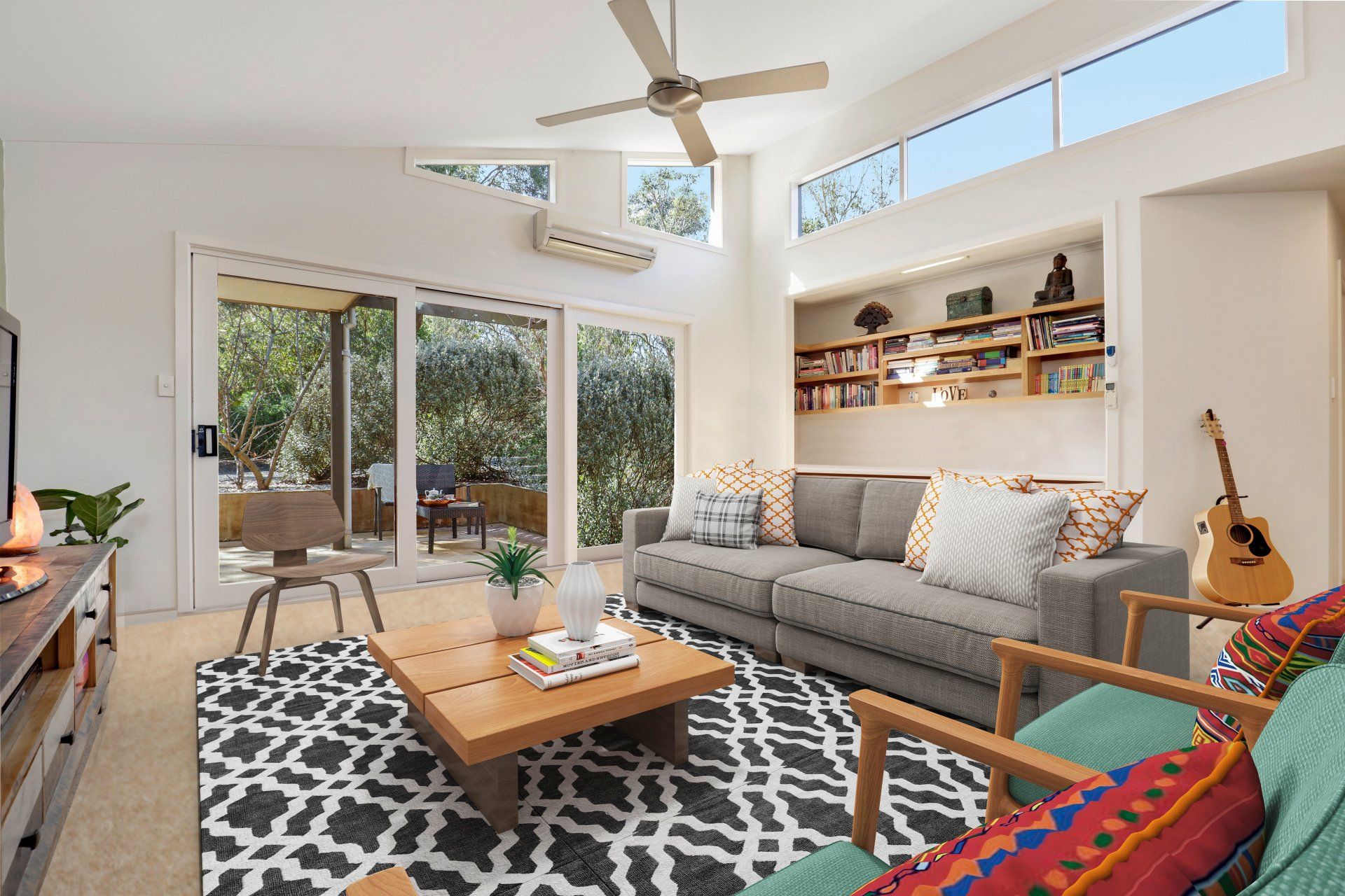 Bright living room with gray sofa, patterned rug, wood coffee table, and sliding glass doors to patio