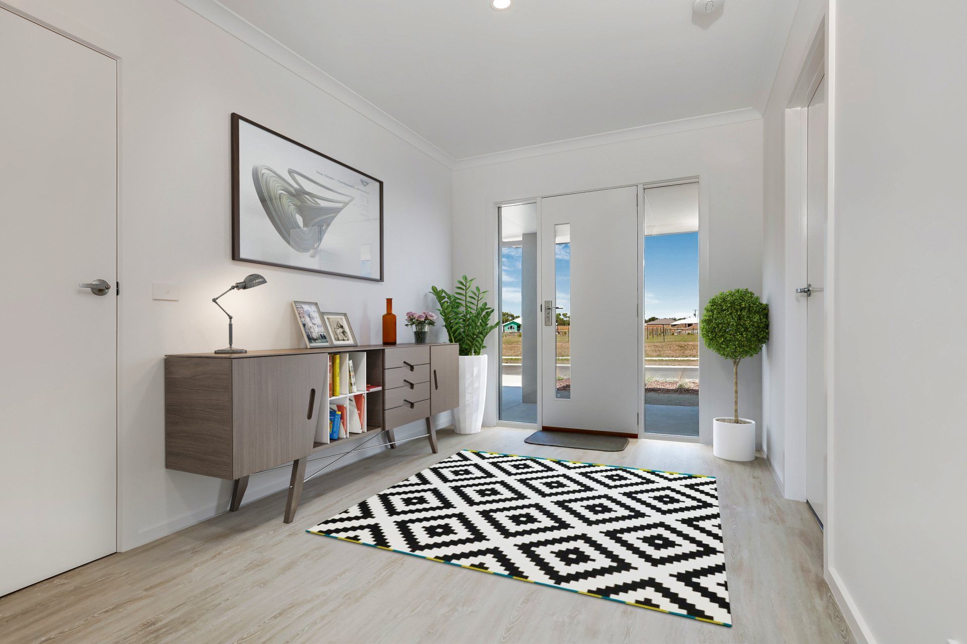 Bright modern hallway with console table, geometric rug, potted plants, and glass doors to the outdoors