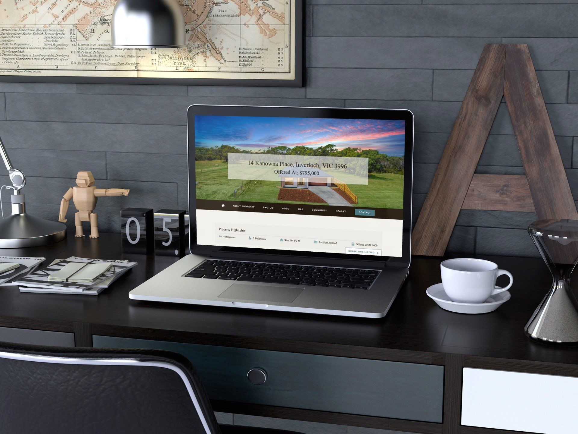Modern desk workspace with open laptop, coffee cup, and decor against a gray wall