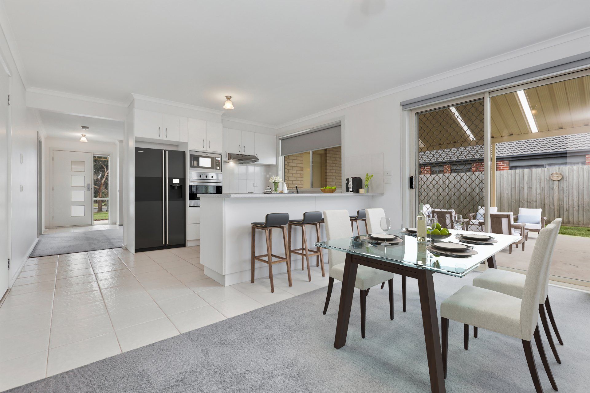 Bright open-plan kitchen and dining area with white cabinets, bar stools, and a table by sliding doors