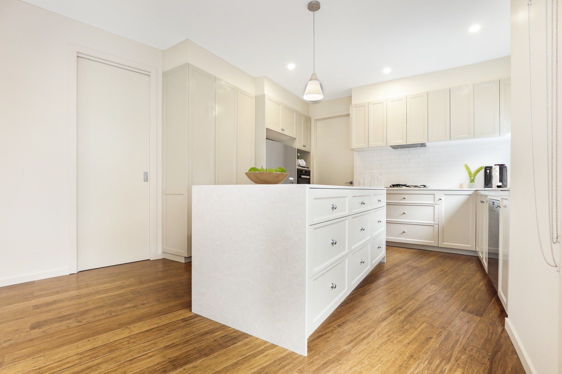 Bright white modern kitchen with wood floors and a central island