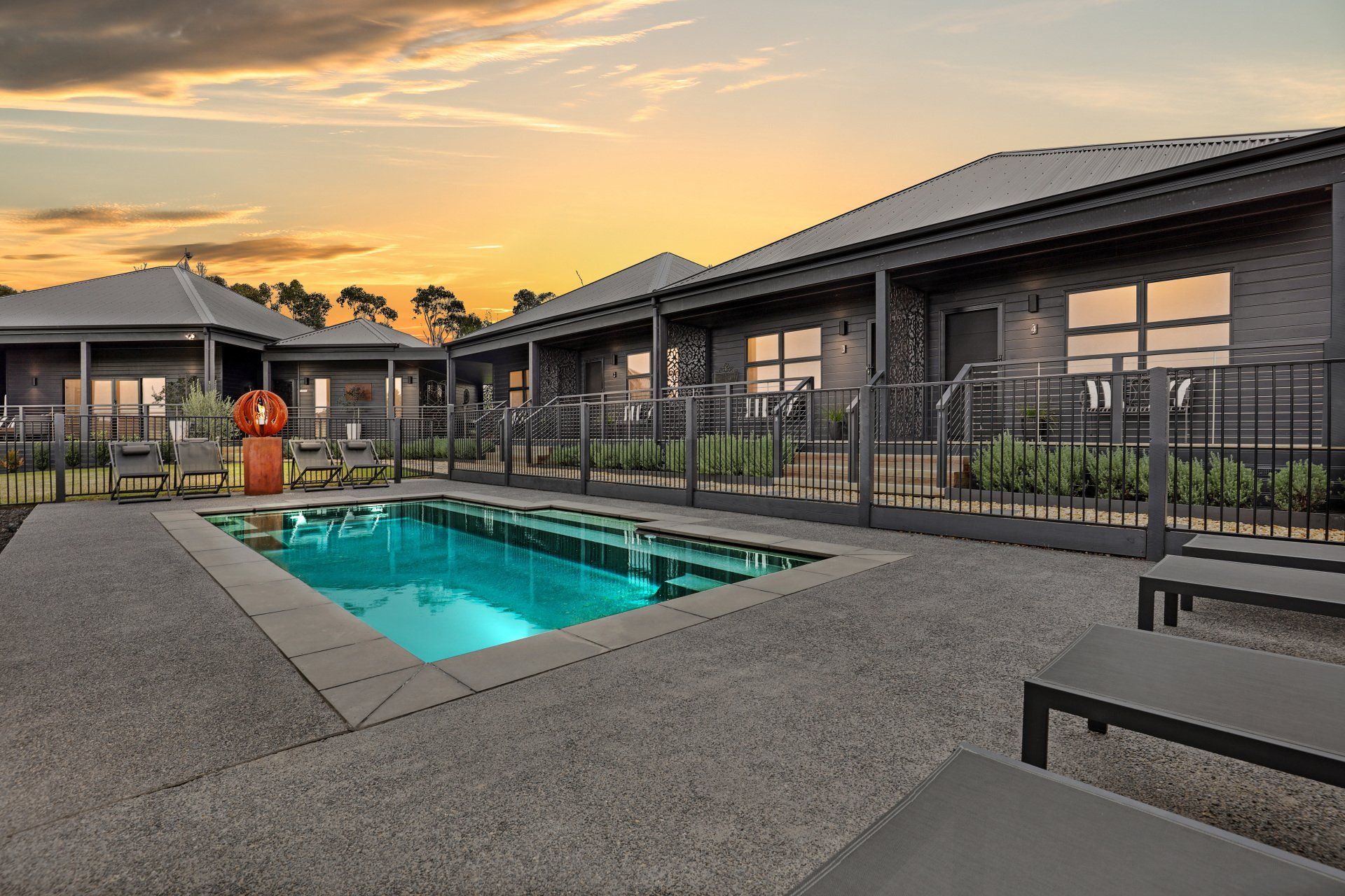 Modern apartment complex courtyard with a lit swimming pool at sunset