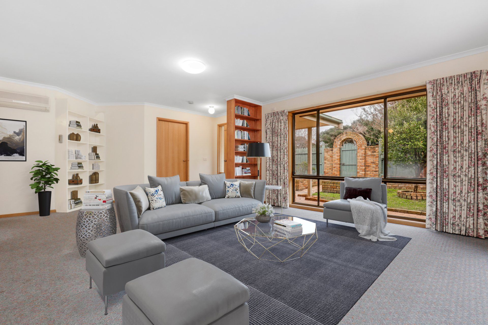 Bright living room with gray sectional sofa, patterned rug, fireplace, and large sliding glass doors.
