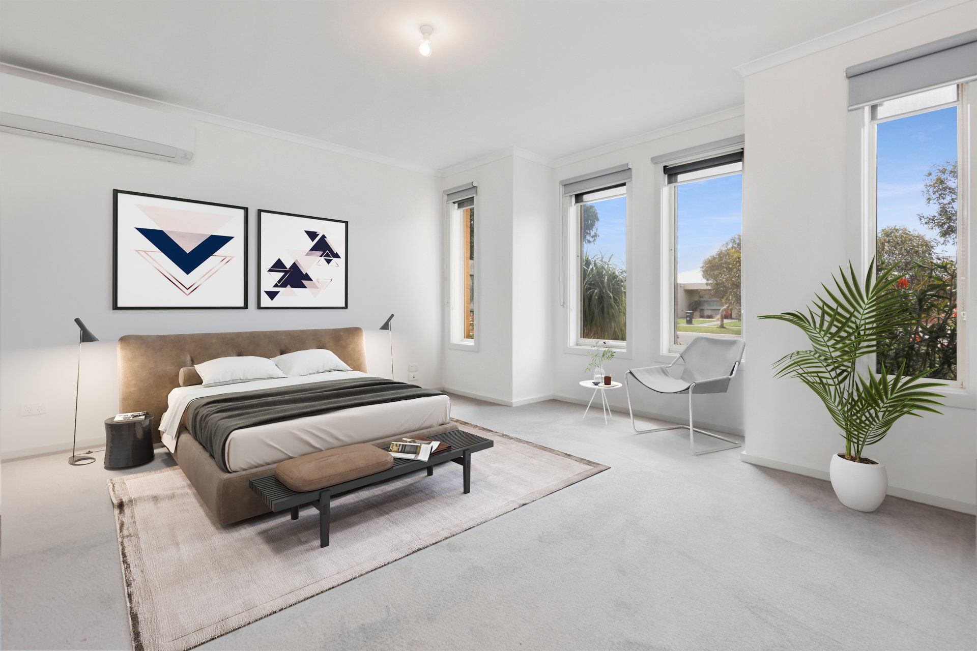 Bright minimalist bedroom with a bed, framed art, white chairs, and large windows overlooking trees.