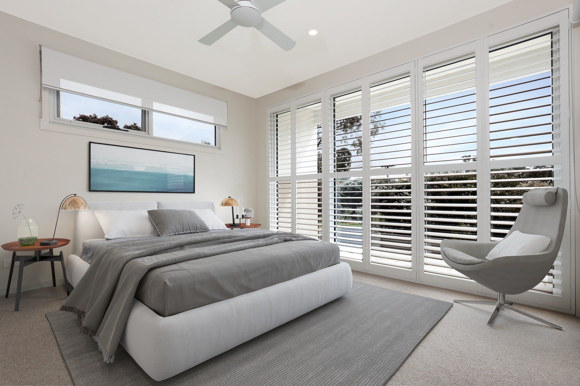 Bright modern bedroom with gray bed, white shutters, and a gray chair by large windows.
