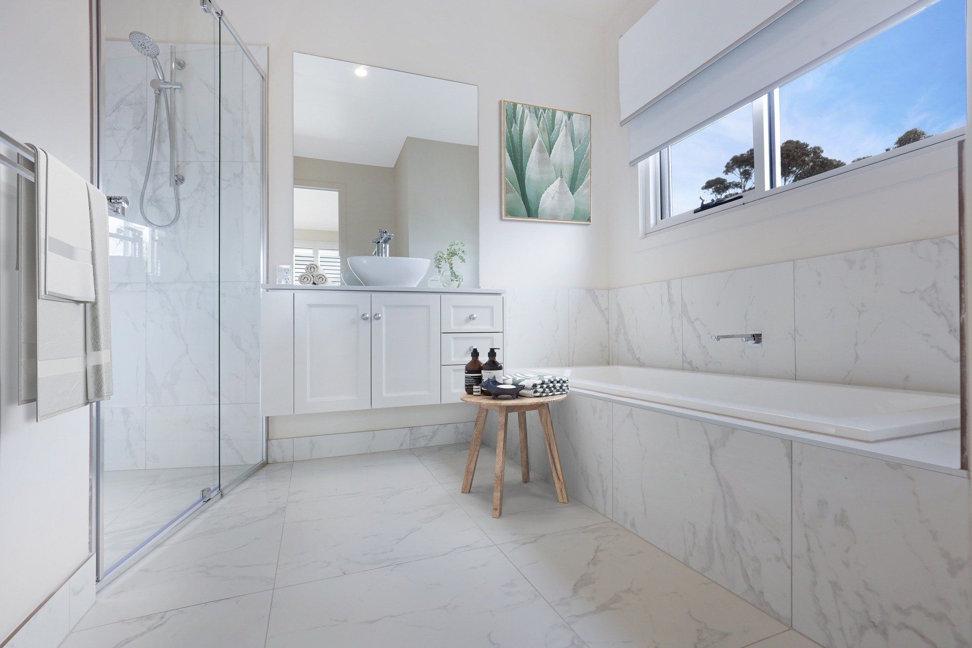 Bright white modern bathroom with glass shower, vanity, tub bench, and large window