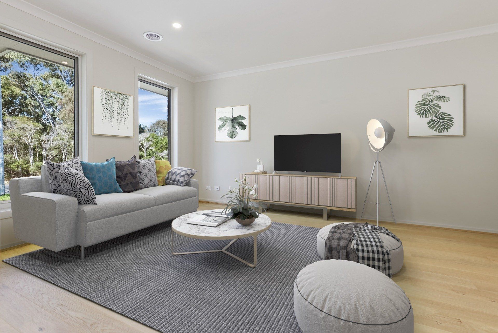 Bright modern living room with gray sofa, TV console, patterned rug, and large window overlooking greenery