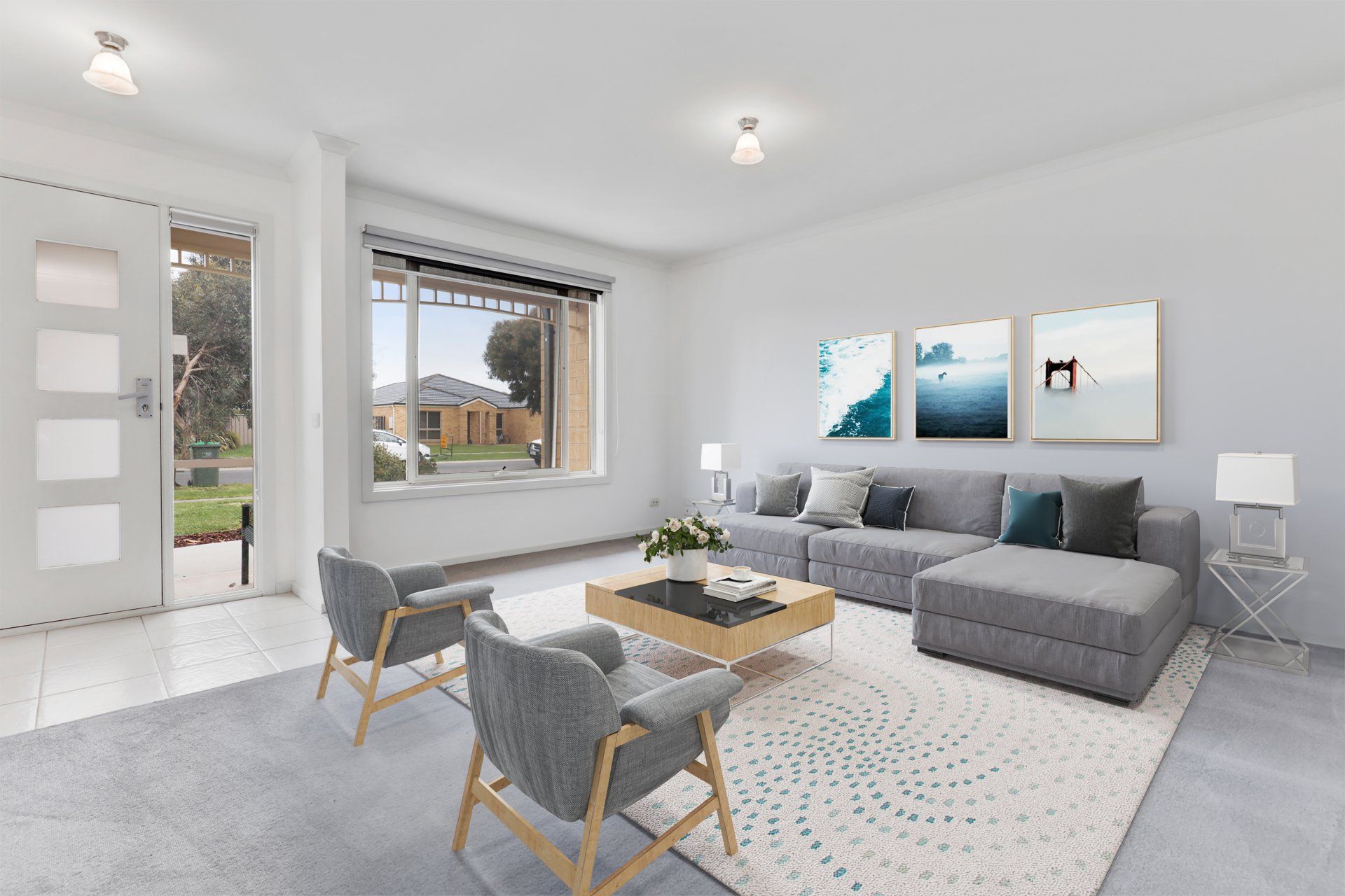 Modern gray living room with sofa, coffee table, armchair, and large window by the front door