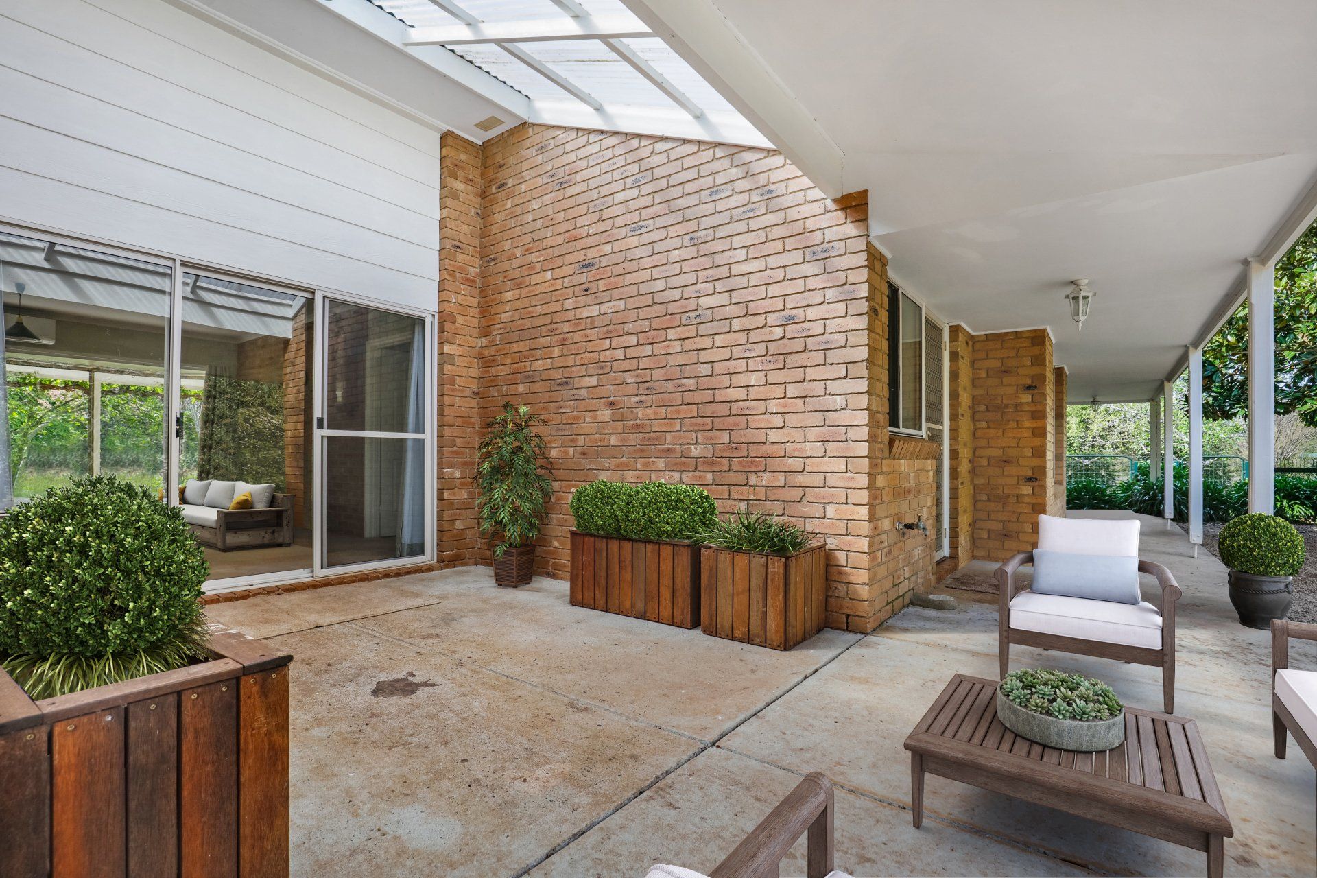 Covered brick patio with outdoor seating, potted plants, and large sliding glass doors